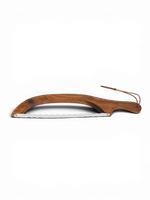 Sourdough Mumma sourdough bread knife with a serrated blade for slicing baked bread, shown on a wooden surface.
